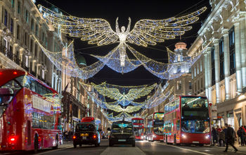 Double-decker buses pass beneath Christmas lights on Regent Street, London, U.K.