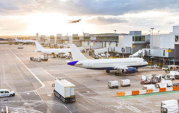 Airport tarmac with airplanes and service vehicles at sunset.