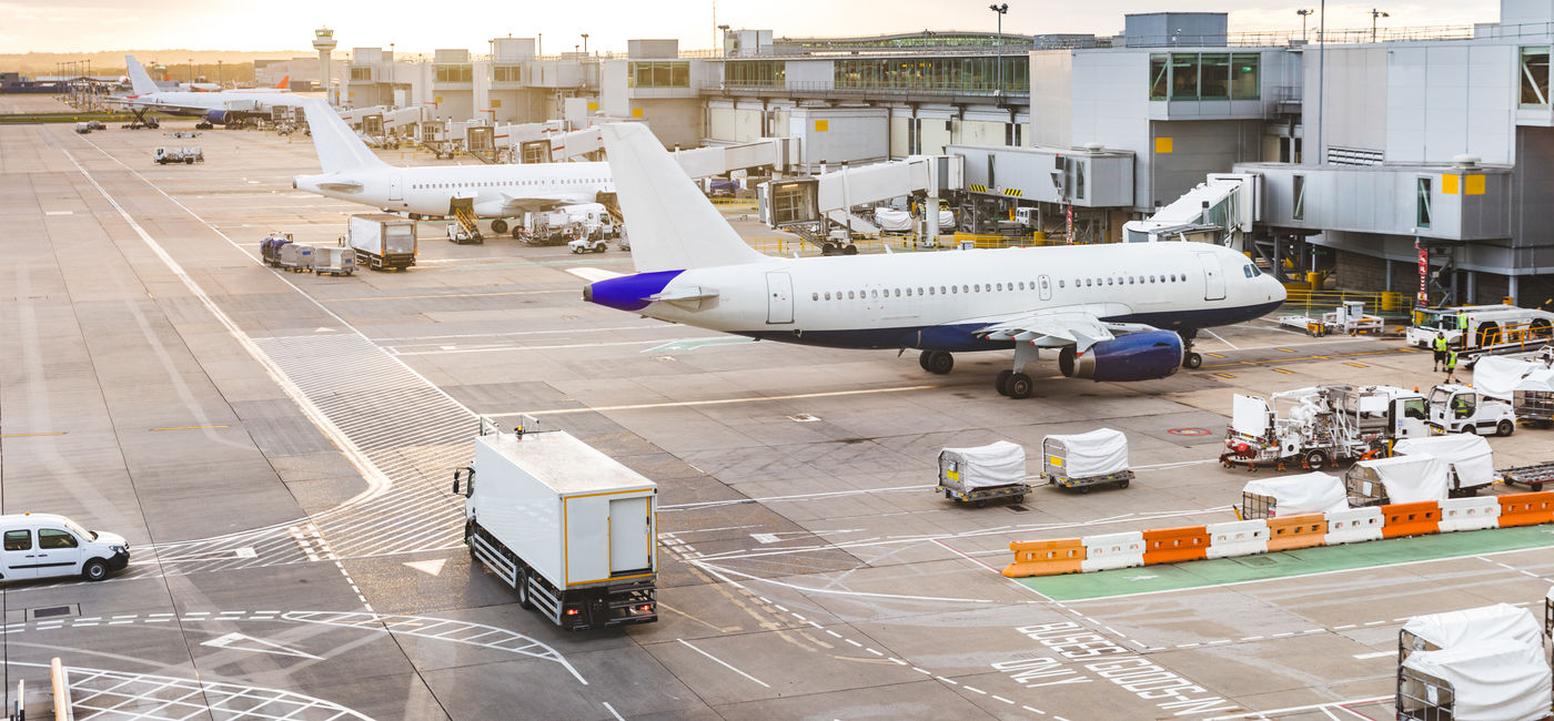 Image: Airport tarmac with airplanes and service vehicles at sunset. (Photo Credit: Adobe Stock/william87)