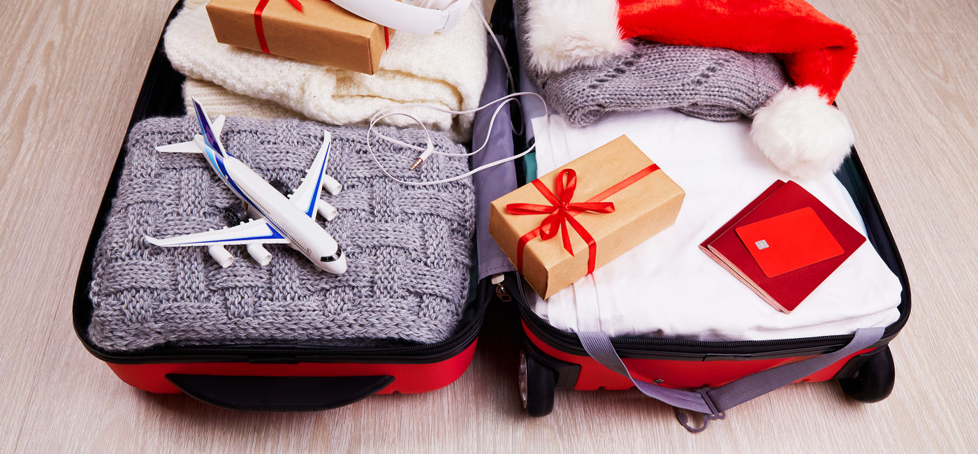 Image: Suitcase with Christmas gifts and a Santa hat. (Photo Credit: Adobe Stock/Viktoriya)