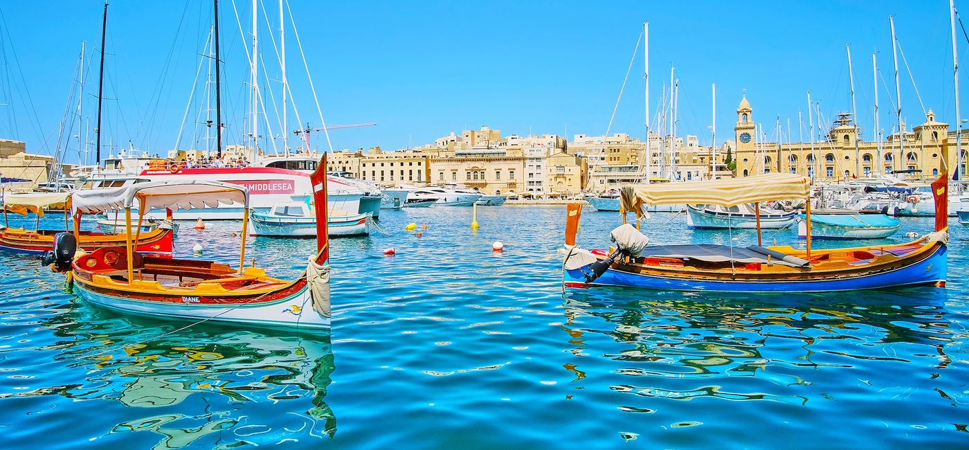 Image: Traditional Maltese boats, called dghajs, with the city of Birgu in the background. (Photo Credit: Malta Tourism Authority)