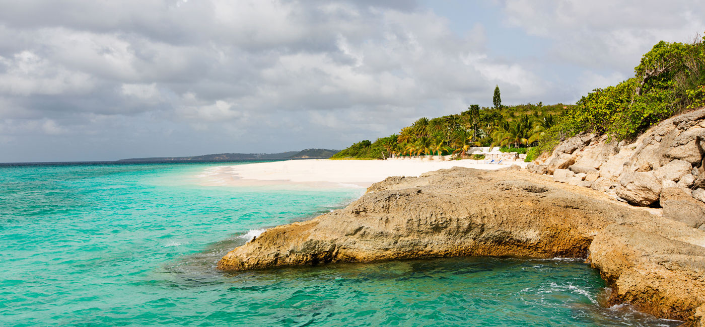 Image: view at rugged rocky seashore and white sand empty beach at anguilla, island in caribbean sea (Photo via noblige / iStock / Getty Images Plus)