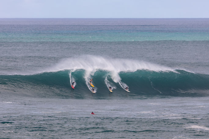 Surfers catching a wave in Waimea Bay on the North Shore of Oahu, Hawaii