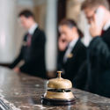 Hotel staff working at reception counter with service bell.