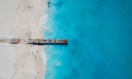 Drone photo of pier in Grace Bay, Providenciales, Turks and Caicos. The caribbean blue sea and white sandy beaches can be seen (photo via JoaoBarcelos / iStock / Getty Images Plus)