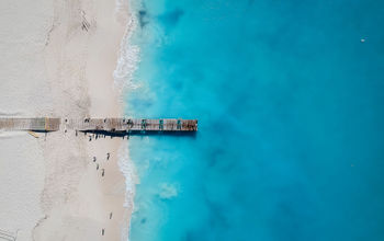Drone photo of pier in Grace Bay, Providenciales, Turks and Caicos. The caribbean blue sea and white sandy beaches can be seen (photo via JoaoBarcelos / iStock / Getty Images Plus)